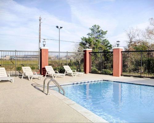 a swimming pool with chairs and a fence at Quality Inn & Suites Bryan-College Station in Bryan