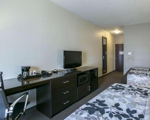a hotel room with a bed and a desk with a television at Sleep Inn & Suites Round Rock - Austin North in Round Rock