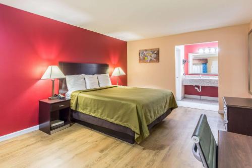 a hotel room with a bed and a red wall at Quality Inn & Suites Bridge City Orange in Bridge City