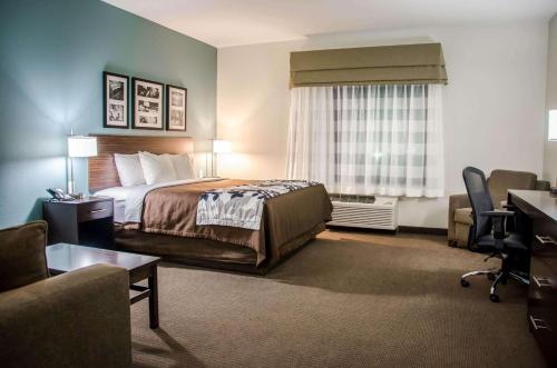 a hotel room with a bed and a desk at Sleep Inn & Suites Center in Center