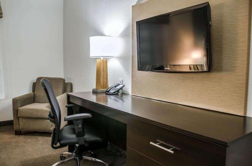 a hotel room with a desk with a television and a chair at Sleep Inn & Suites Center in Center
