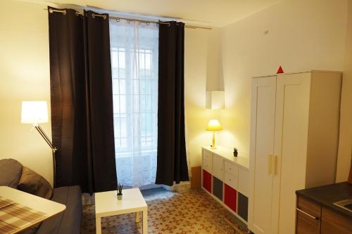- un salon avec une grande fenêtre et des rideaux noirs dans l'établissement Studio charmant intra-muros, à Avignon