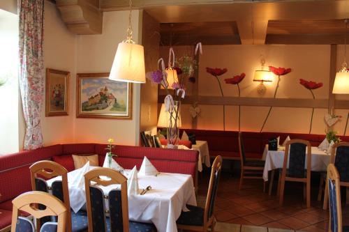 a dining room with tables and chairs and flowers on the wall at Mohnhotel - Bergwirt Schrammel in Zwettl Stadt