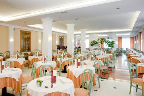 una sala da pranzo con tavoli e sedie con tovaglie bianche di Hotel Terme Millepini a Montegrotto Terme