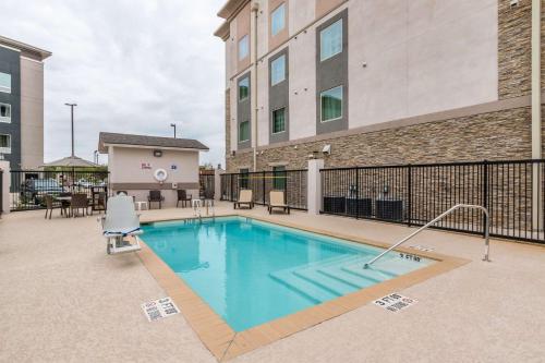 a swimming pool with a chair and a building at Sleep Inn & Suites College Station near University in College Station