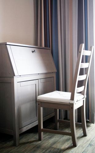 a wooden chair next to a dresser with a desk at Hotel Admiral Scheer in Laboe