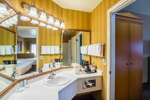 a bathroom with a sink and a large mirror at Clarion Suites St George - Convention Center Area in St. George