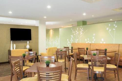 a restaurant with tables and chairs and a flat screen tv at Sleep Inn & Suites Ingleside - Corpus Christi in Ingleside