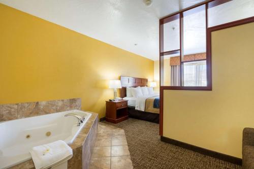 a hotel room with a bath tub and a bed at Comfort Inn & Suites in Cedar City