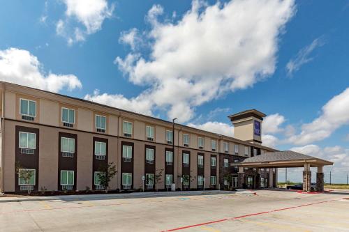 a large brown building with a clock tower next to a parking lot at Sleep Inn & Suites Ingleside - Corpus Christi in Ingleside