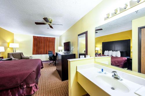 Cette chambre comprend un lit et un lavabo. dans l'établissement Rodeway Inn & Suites, à Monticello