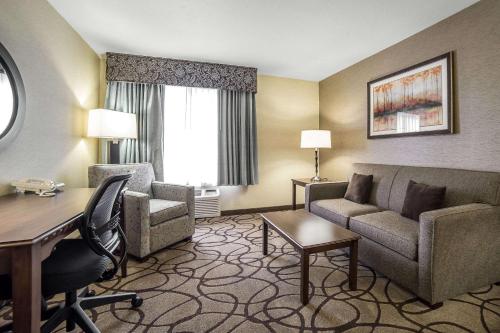 a hotel room with a desk and a couch and chair at Comfort Suites Salt Lake City Airport in Salt Lake City