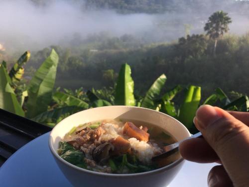 a person holding a bowl of food on a table at Home OK Taleymok in Khao Kho