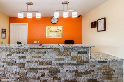an orange wall with a stone counter with a clock at Econo Lodge Near Motor Speedway in Bristol