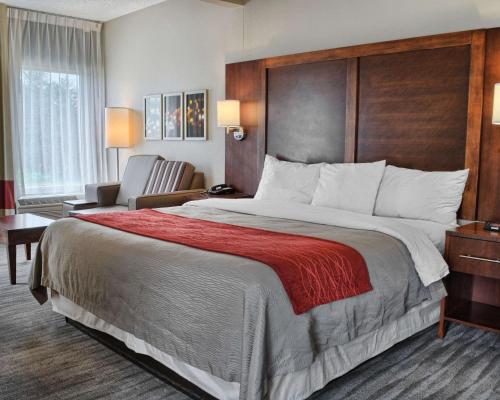 a hotel room with a large bed and a chair at Comfort Inn Ruther Glen near Kings Dominion in Ruther Glen