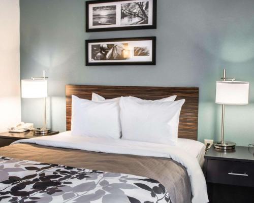 a bedroom with a bed with two lamps and two pictures on the wall at Sleep Inn & Suites Monticello in Charlottesville