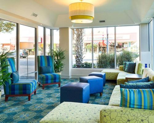 a lobby with blue chairs and couches and windows at Comfort Suites Beachfront in Virginia Beach