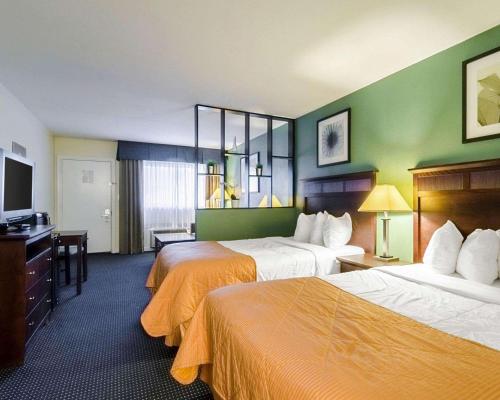 um quarto de hotel com duas camas e uma televisão de ecrã plano em Rodeway Inn & Suites Williamsburg Central em Williamsburg