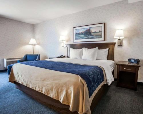 a hotel room with a large bed and a blue chair at Comfort Inn Bellingham in Bellingham