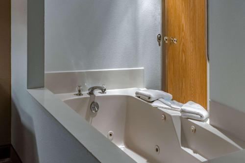 a white bath tub in a bathroom with a mirror at Quality Inn & Suites Vancouver North in Vancouver