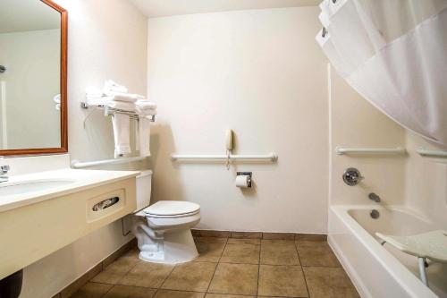 a bathroom with a toilet and a sink and a tub at FairBridge Inn & Suites Sunnyside in Sunnyside