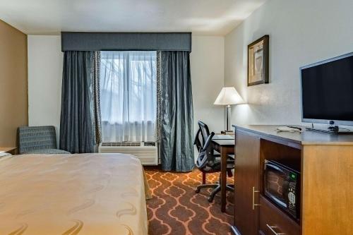 a hotel room with a bed and a television and a desk at Quality Inn & Suites Vancouver North in Vancouver