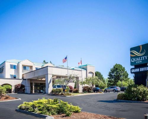 an office building with an american flag in front of it at Quality Inn Grand Suites Bellingham in Bellingham