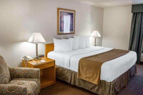 a hotel room with a large bed and a chair at Quality Inn & Suites Longview Kelso in Longview