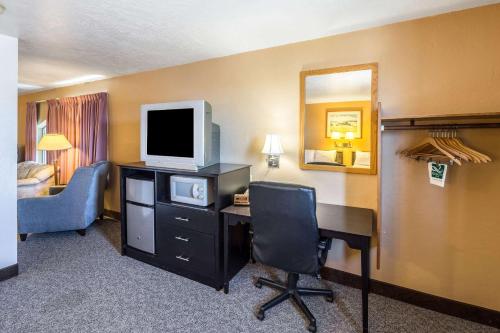 a hotel room with a desk with a tv and a chair at Quality Inn in Moses Lake