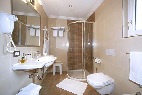 ein Bad mit einem Waschbecken, einer Dusche und einem WC in der Unterkunft Villa Seceda in Wolkenstein in Gröden