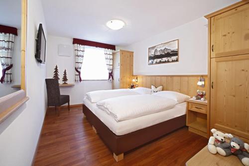 a bedroom with a large bed and a desk at Villa Seceda in Selva di Val Gardena