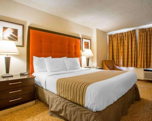 a hotel room with a bed, chair, and nightstand at Econo Lodge Inn & Suites Stevens Point in Stevens Point