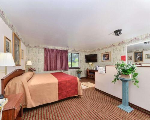 a hotel room with a bed and a desk at Rodeway Inn & Suites Madison East in Madison