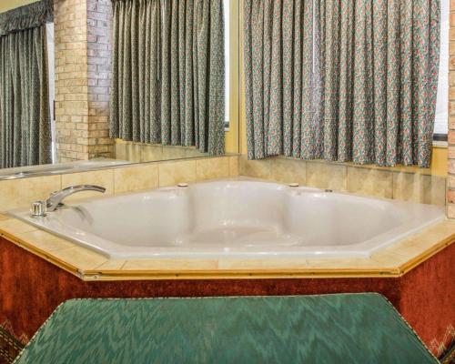 bañera grande en una habitación con cortinas en Quality Inn Central Wisconsin Airport en Mosinee