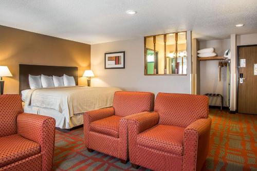 a hotel room with a bed and two chairs at Quality Inn & Suites in West Bend