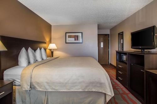 a hotel room with a bed and a flat screen tv at Quality Inn & Suites in West Bend