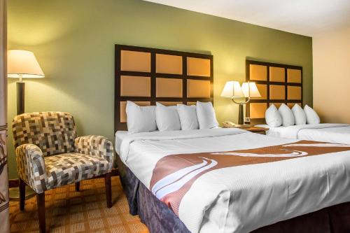 a hotel room with two beds and a chair at Quality Inn & Suites Marinette in Marinette