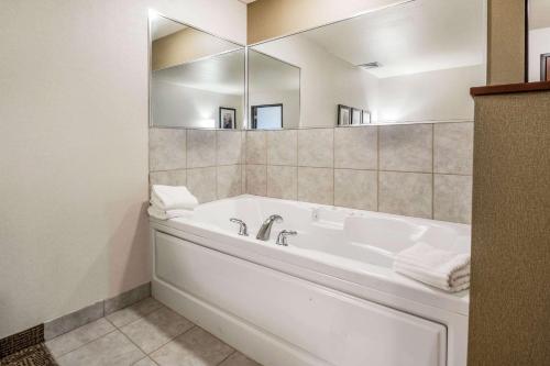 a white bath tub in a bathroom with a mirror at Comfort Suites at Par 4 Resort in Waupaca