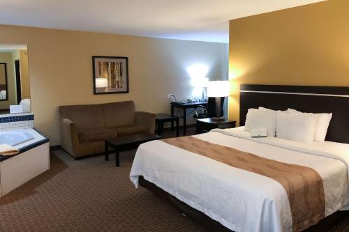 a hotel room with a large bed and a chair at Quality Inn & Suites Sun Prairie Madison East in Sun Prairie