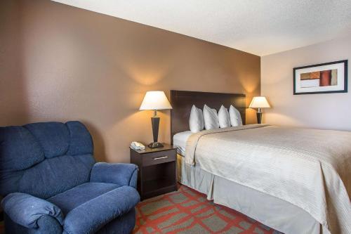 a hotel room with a bed and a blue chair at Quality Inn & Suites in West Bend