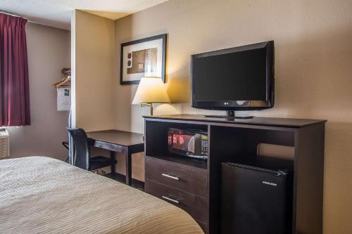 a hotel room with a bed and a flat screen tv at Quality Inn & Suites in West Bend