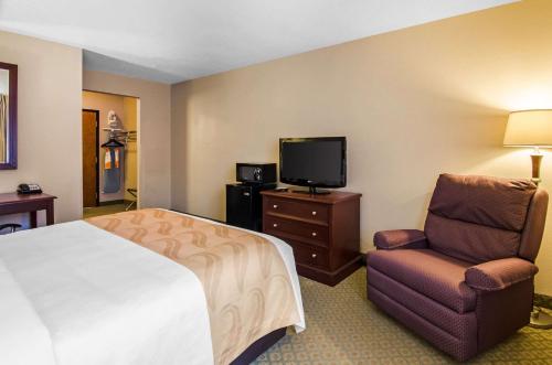 a hotel room with a bed and a chair at Quality Inn Summersville - New River Area in Summersville
