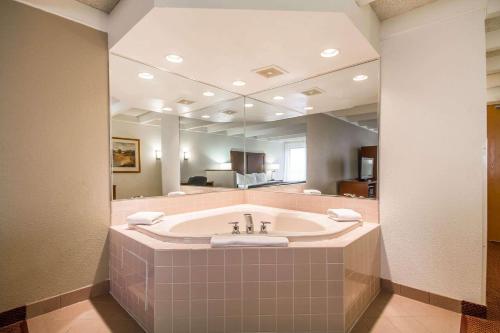 ein Badezimmer mit einer Badewanne und einem großen Spiegel in der Unterkunft Comfort Inn & Suites Madison - Airport in Madison