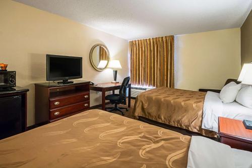 a hotel room with two beds and a desk with a television at Quality Inn Fairmont in Fairmont