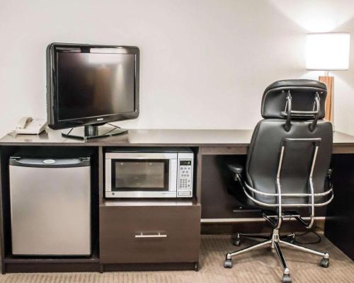 a desk with a computer and a microwave and a chair at Sleep Inn in Summersville