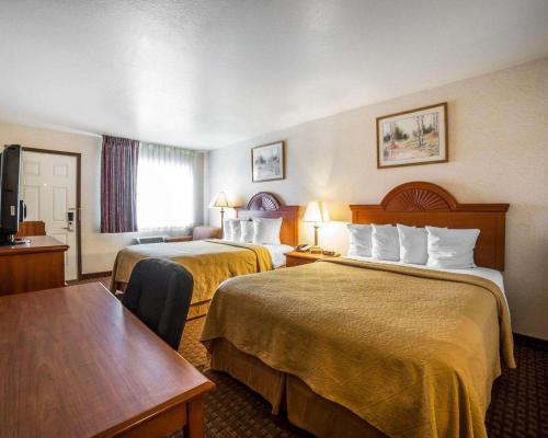 Habitación de hotel con 2 camas y mesa en Quality Inn Sheridan, en Sheridan