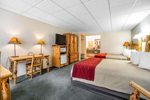 a bedroom with two beds and a desk and a television at Rodeway Inn Pronghorn Lodge in Lander