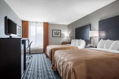 a hotel room with two beds and a flat screen tv at Quality Inn & Suites Brownsburg - Indianapolis West in Brownsburg