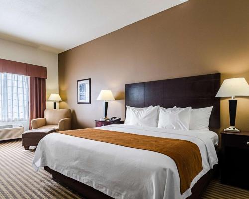 a hotel room with a large bed and a chair at Comfort Inn & Suites Lawrence - University Area in Lawrence