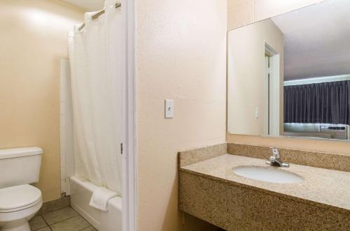 La salle de bains est pourvue d'un lavabo, de toilettes et d'un miroir. dans l'établissement Executive Inn Dodge City, KS, à Dodge City